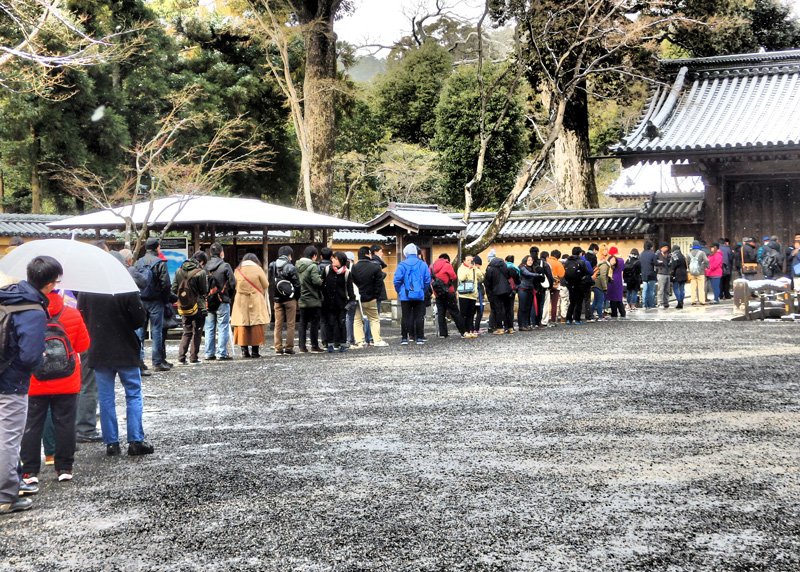 雪の積もった金閣寺に並ぶ人々